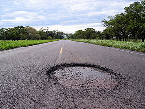 A large pothole on a country road.